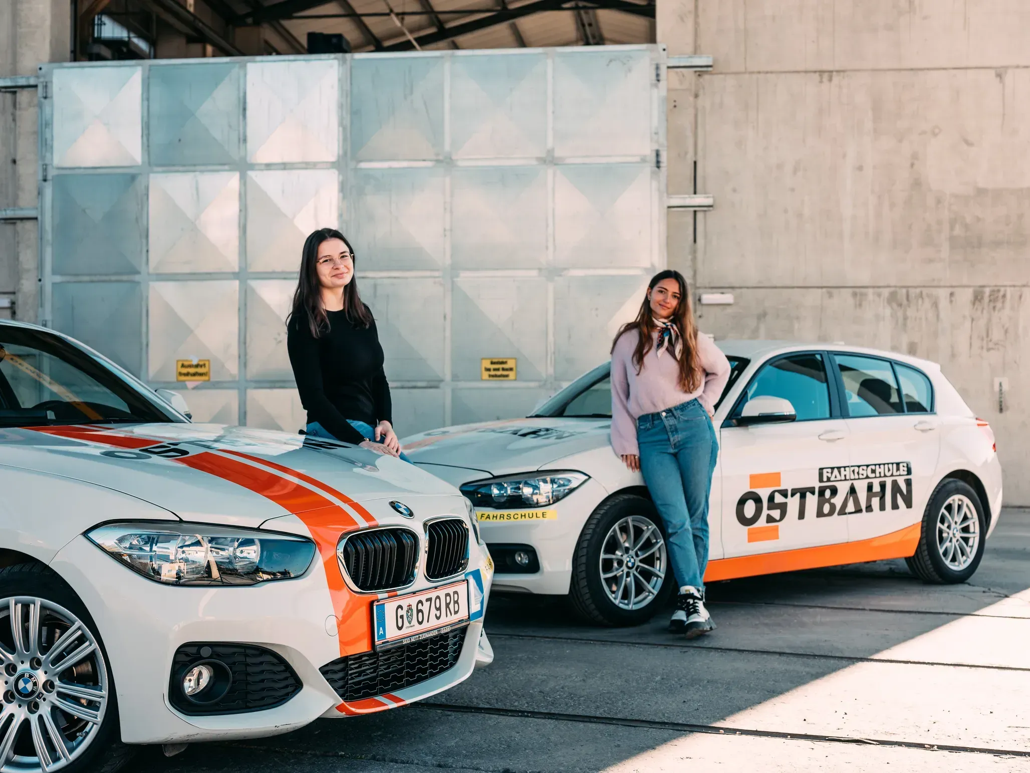 Zwei Fahrschülerinnen bei zwei Fahrschulautos der Fahrschule Ostbahn