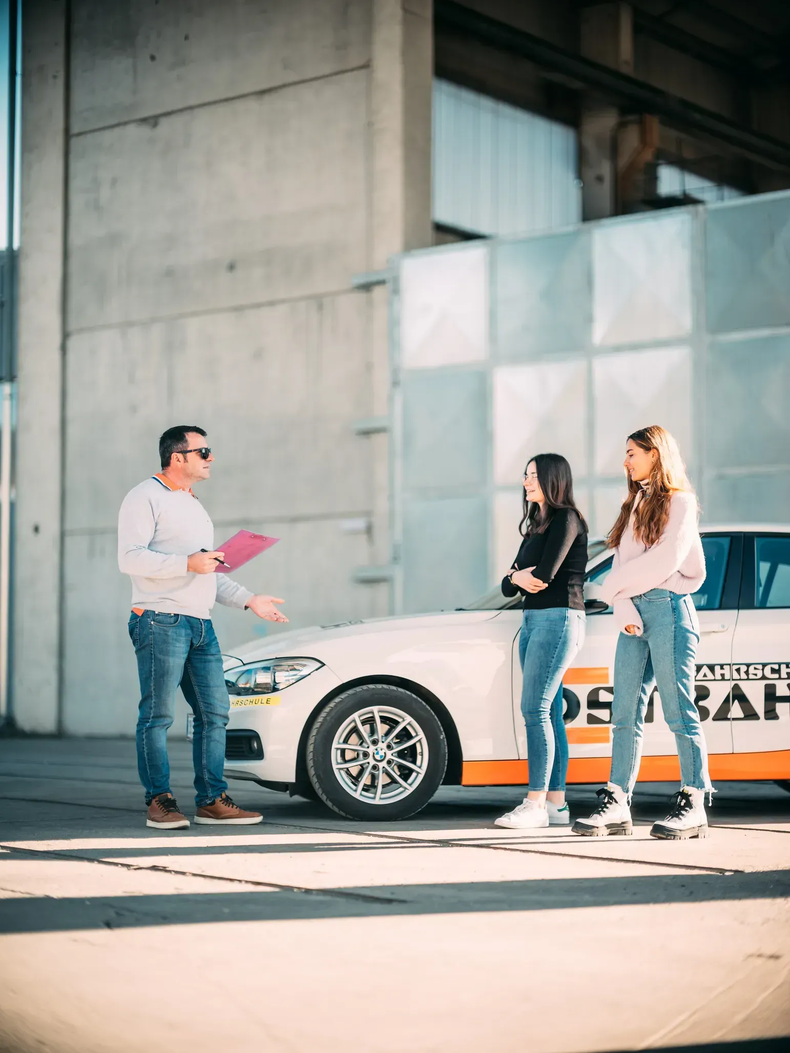 Ein Fahrlehrer bespricht sich mit zwei Fahrschülerinnen