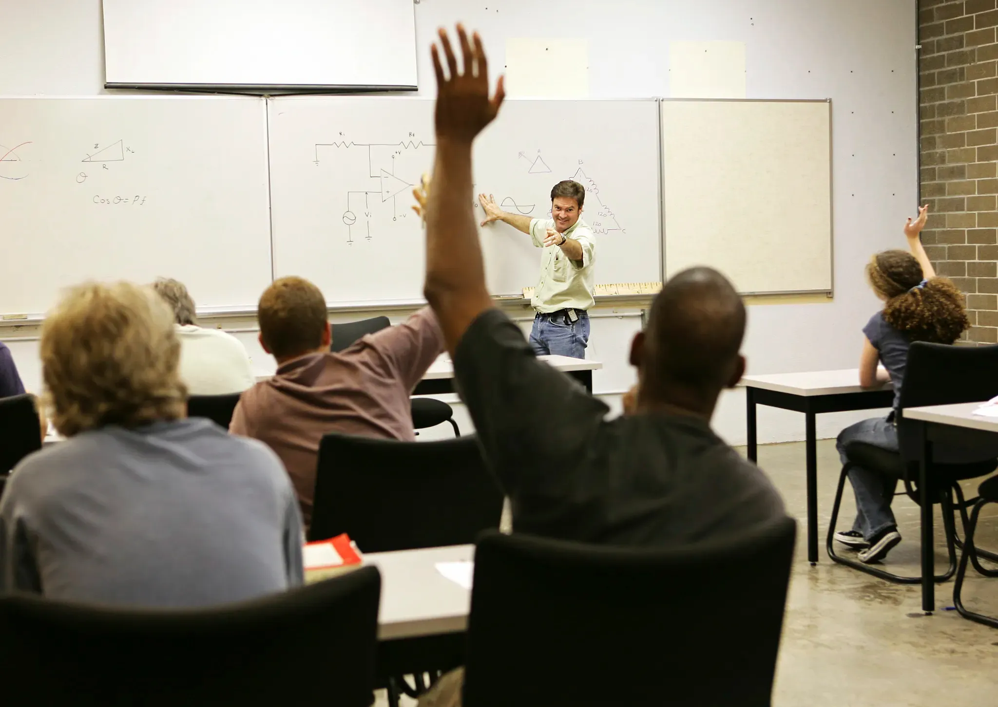 Fahrschüler:innen im Theoriekurs, einer zeigt auf